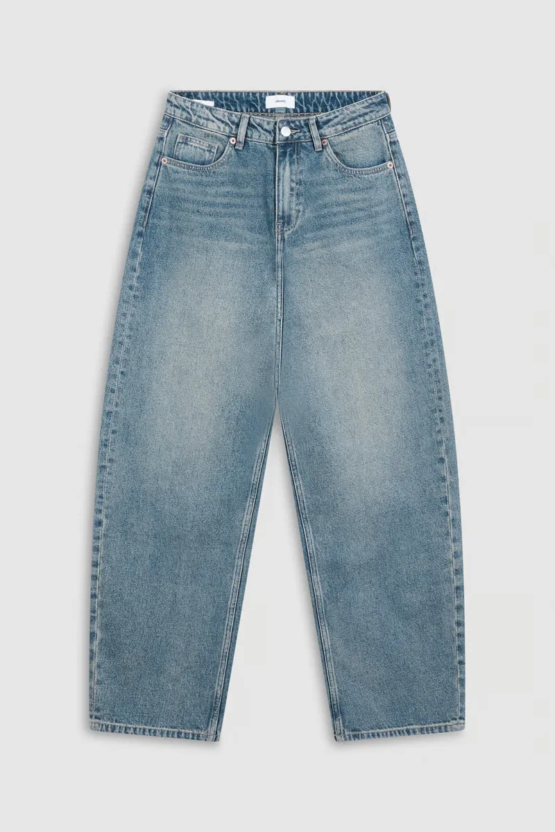 Light wash barrel leg jeans photographed flat on a plain grey background