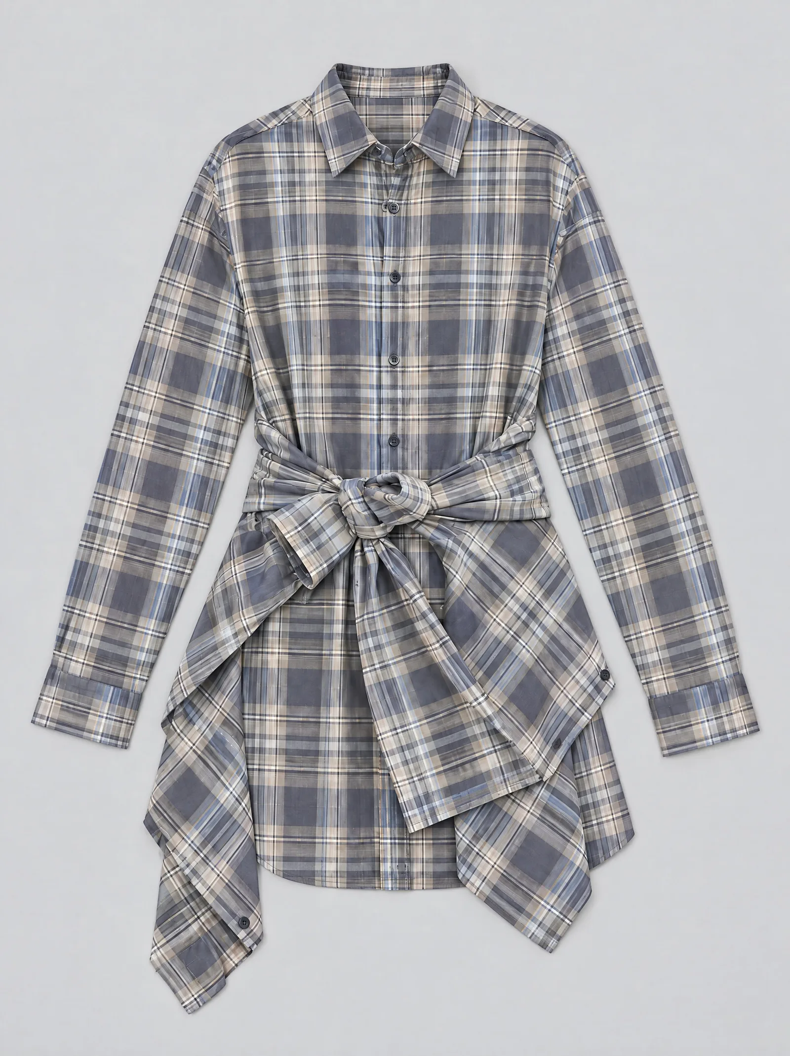 An oversized blue and tan plaid shirt dress laid flat on a plain light grey surface, photographed from directly above